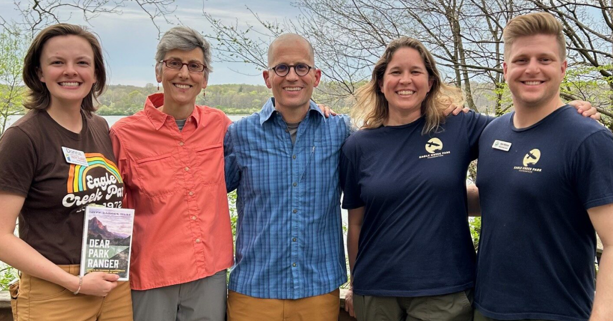 A group of five park rangers and staff members posing together outdoors, showcasing teamwork and community engagement in a natural setting.