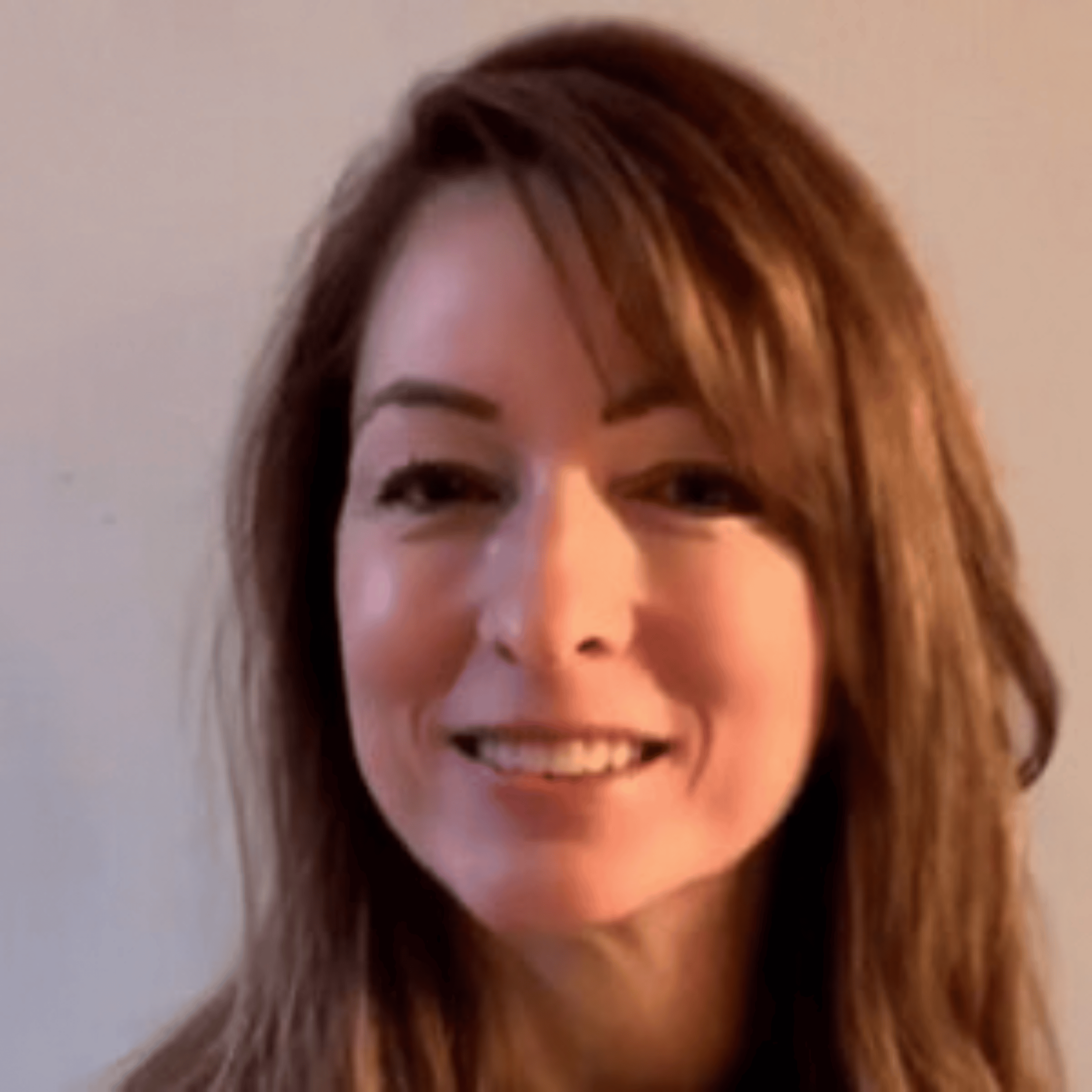 Headshot of a woman with long brown hair and a slight smile against a neutral background.